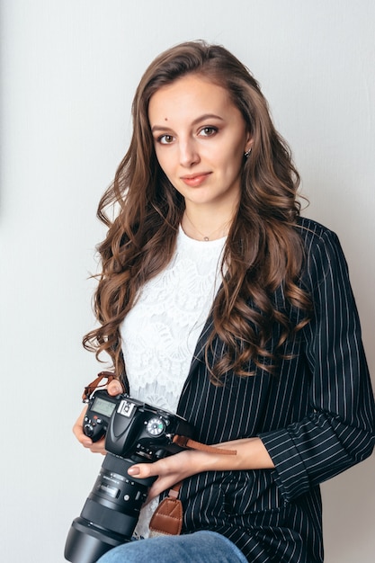 Girl in a jacket with a camera on a white