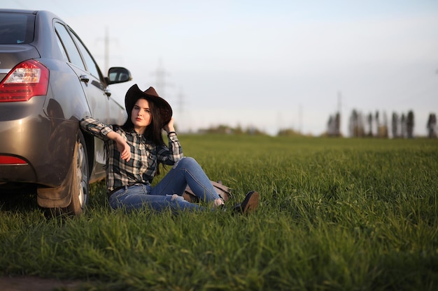 Una ragazza in jeans e cappello viaggia l'estate in campagna