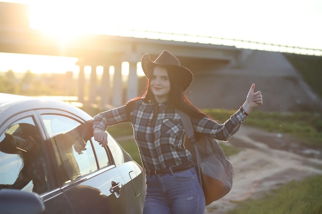 Una ragazza in jeans e cappello viaggia l'estate in campagna