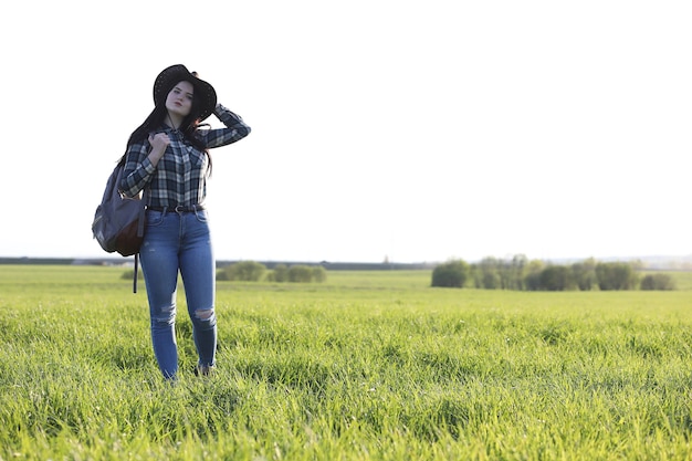 A girl in jeans and a hat travels the summer in the country