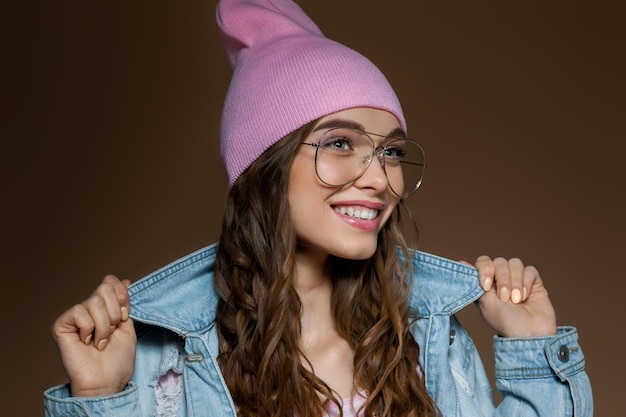 Ragazza in jeans giacca un cappello rosa e occhiali alla moda