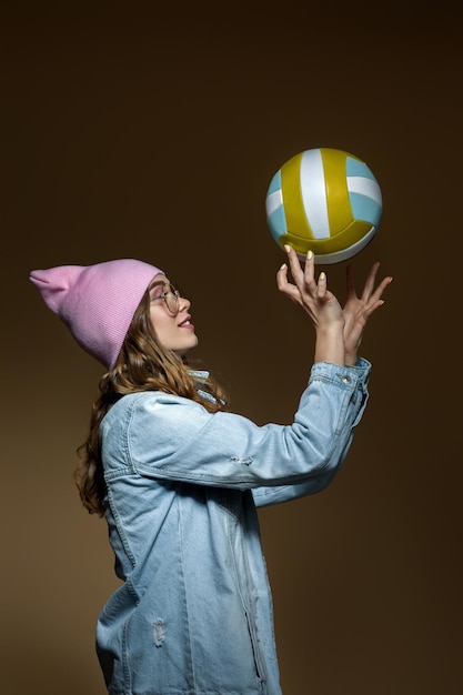 Girl in jeans a pink hat and stylish glasses with a ball