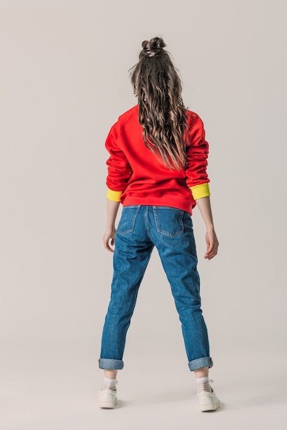 Girl in jeans and red sweatshirt standing back