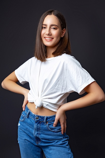 Girl in jeans and a t-shirt in the studio on black