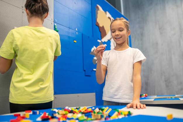 Girl joyfully looking at detail of lego constructor