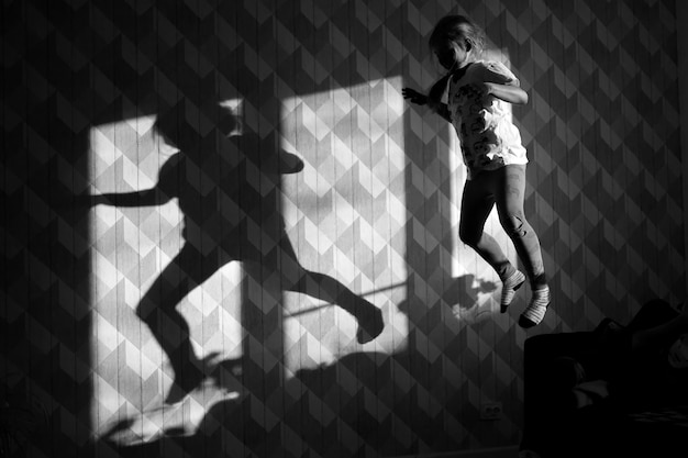 Girl jumping in front of the wall and her shadow is on the wall