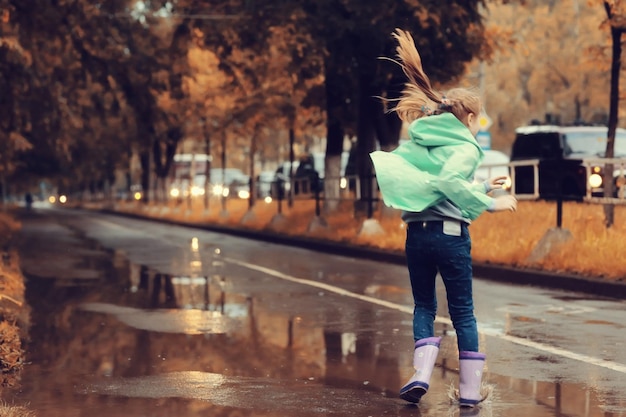 girl jumping in the puddles in the autumn rain