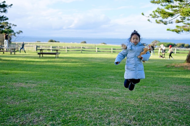 A girl jumps in a park with a toy in her hand.