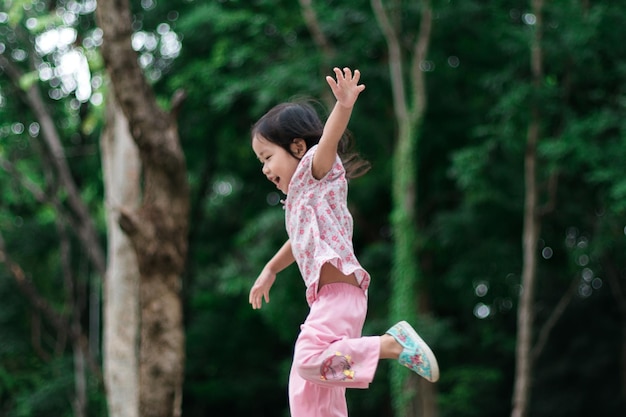 女の子が公園のトランポリンでジャンプする