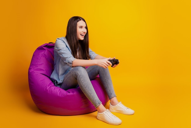 La ragazza tiene il joystick in mano mentre gioca ai videogiochi sit beanbag