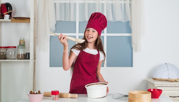 Girl kid in chef apron and hat cooking bakery