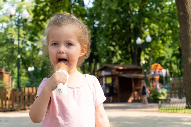 公園でアイスクリームを食べる女児。晴れた夏の日