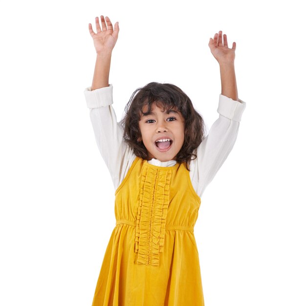 Girl kid and excited with arms up for celebration party and happiness on white background Cheers positivity and energy with youth winner and goals with yes reaction achievement and success