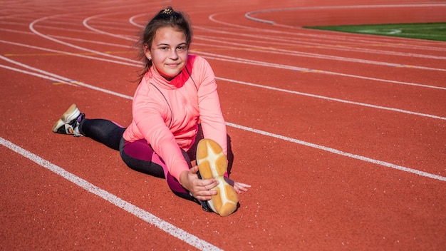 girl kid training sport outside on stadium arena sit in split, flexibility.