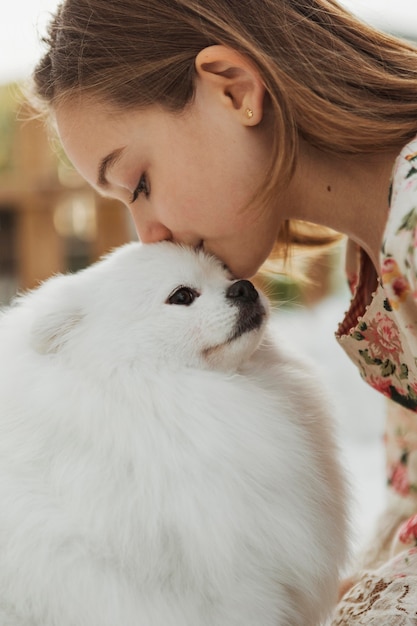 Girl kissing her cute white puppy