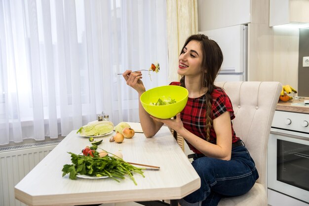 건강한 생활 방식을 위해 야채 샐러드를 먹는 부엌의 소녀