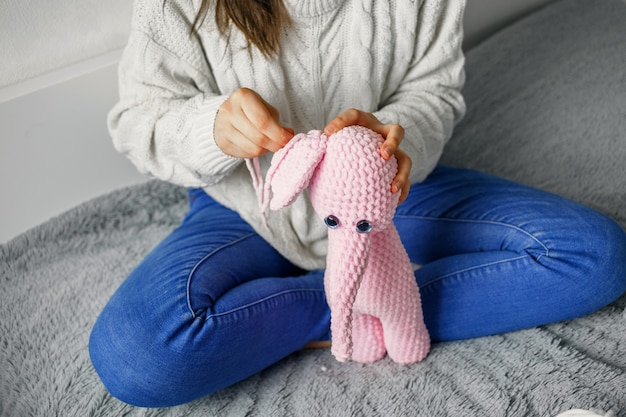 Girl knits a toy of pink yarn