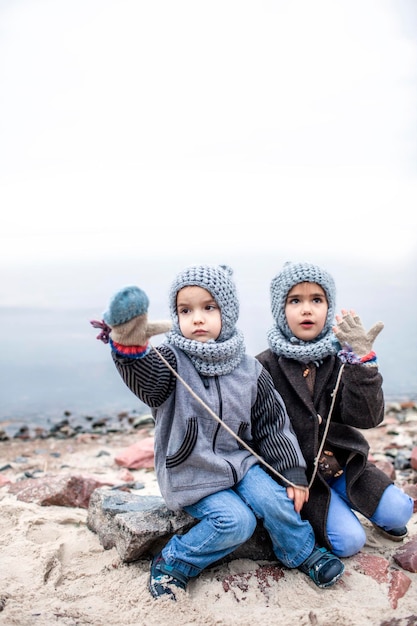 Girl in knitted grey hat sharing gloves with her frozen brother