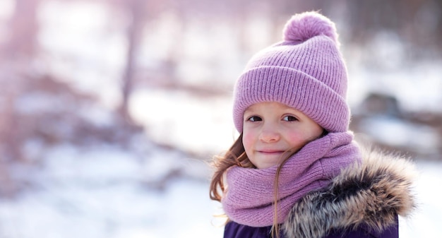 ニットの帽子をかぶった女の子と路上でのスヌードが微笑んでカメラを見る