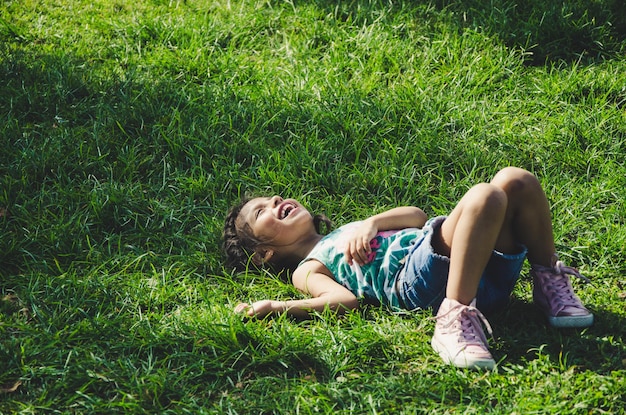 Photo girl laughing while lying on grassy field