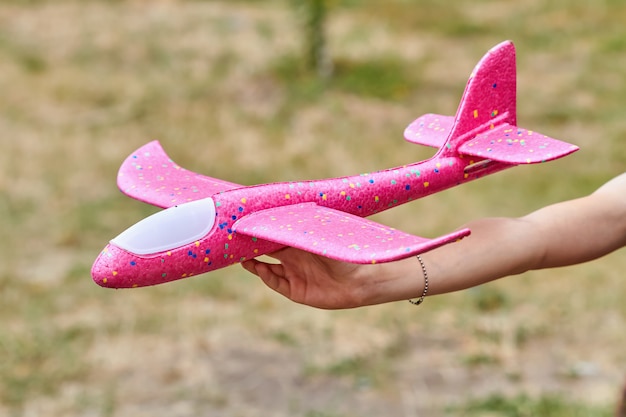 Girl launching a pink toy plane into the air