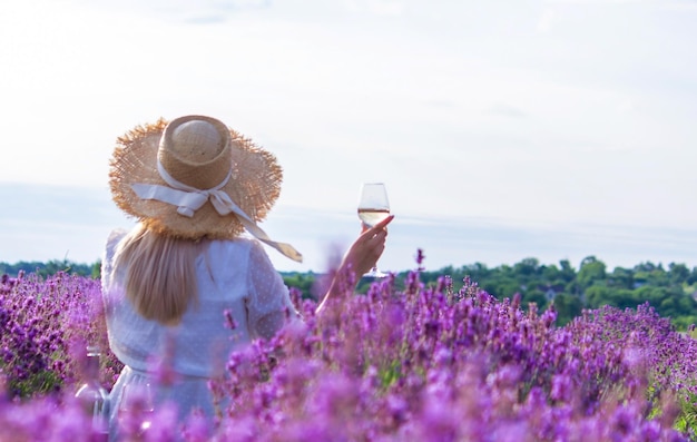 Una ragazza in un campo di lavanda versa il vino in un bicchiere rilassamento
