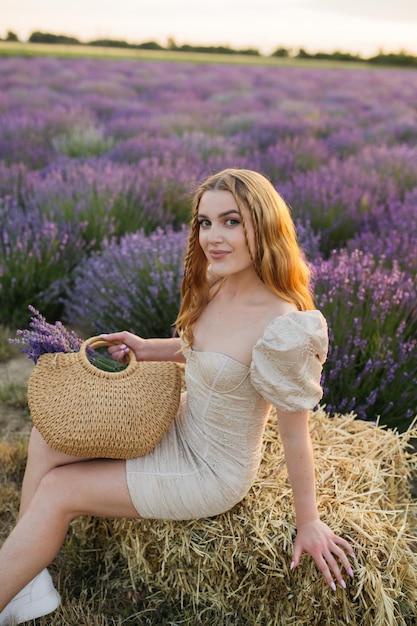 Ragazza in un campo di lavanda donna in un campo di fiori di lavanda al tramonto in un abito bianco francia provenza