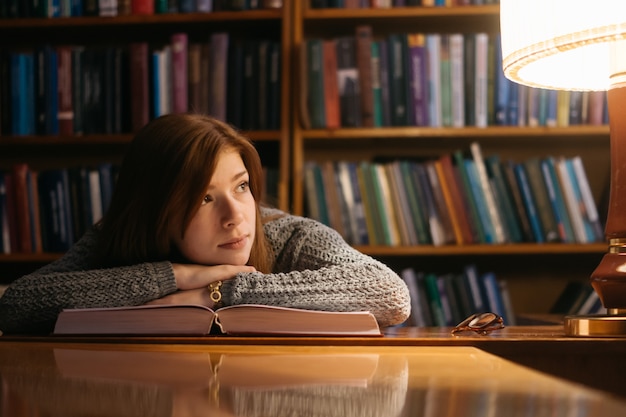 The girl leaned on the book. The girl in the library