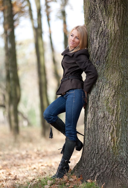 Girl leaning against a tree in the autumn park