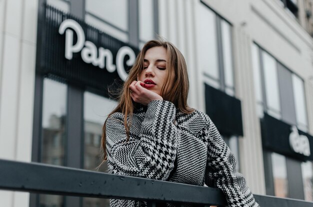 the girl leans on the railing near the building