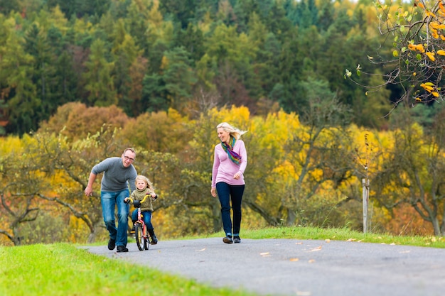 Girl learning bicycling in fall or autumn park 