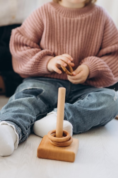 The girl learns colors by playing with wooden cylindrical toy colored human figures and placing them in cups of the appropriate color The child is happy that he completed the task correctly