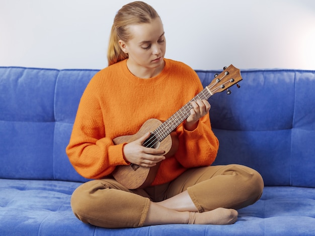 Foto la ragazza impara a suonare l'ukulele a casa