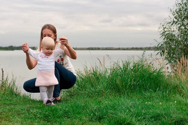 Девочка учится гулять с мамой на природе.