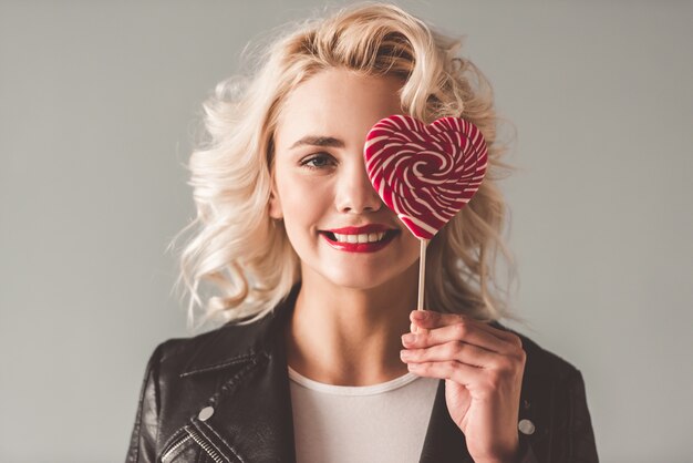 Girl in leather jacket is holding a heart shaped lollipop