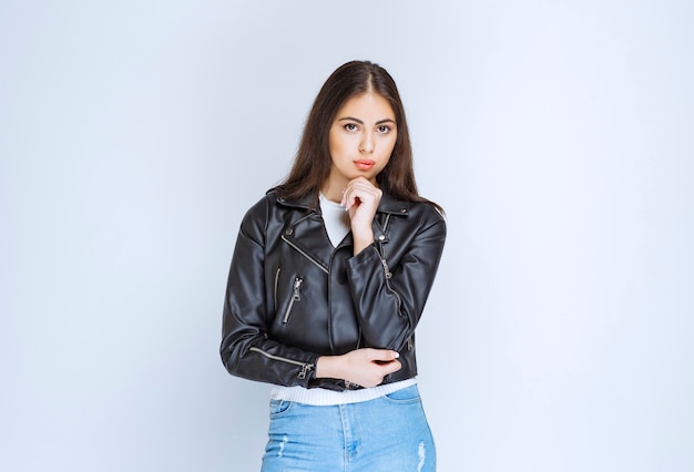 Girl in leather jacket looks thoughtful. 