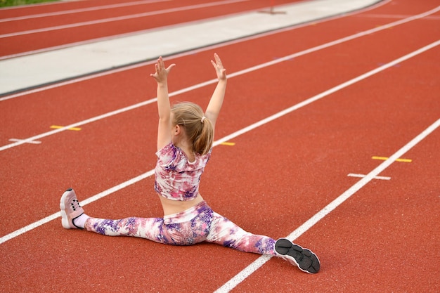 Girl in a leggingstracksuit doing splits at the stadium