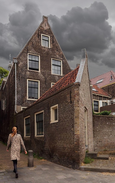 A girl in a leopard coat walks past a church on an overcast day in Holland, Netherlands