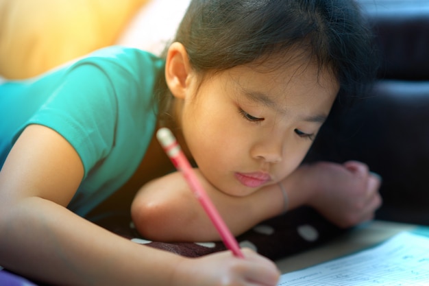 Girl lies down for writing notebook on floor