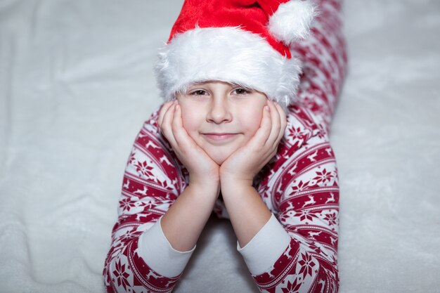 Girl lies in New Year's pajamas and Santa Claus cap