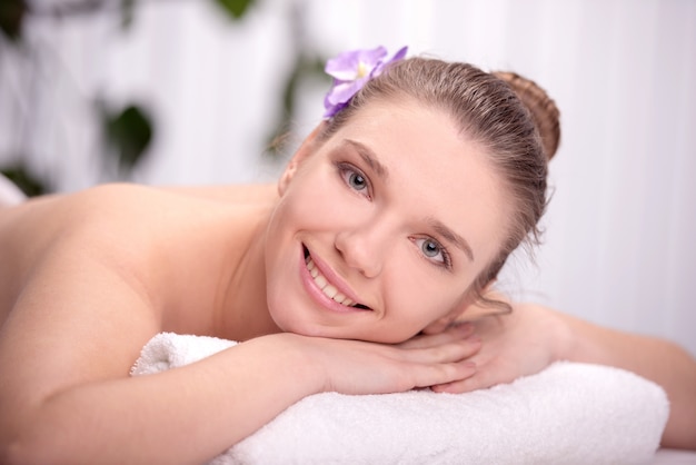 The girl lies in the spa salon and smiling.