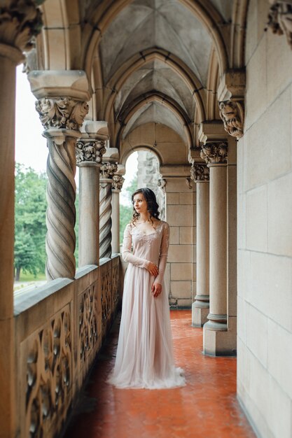 A girl in a light pink dress against the background of a medieval Polish stone castle