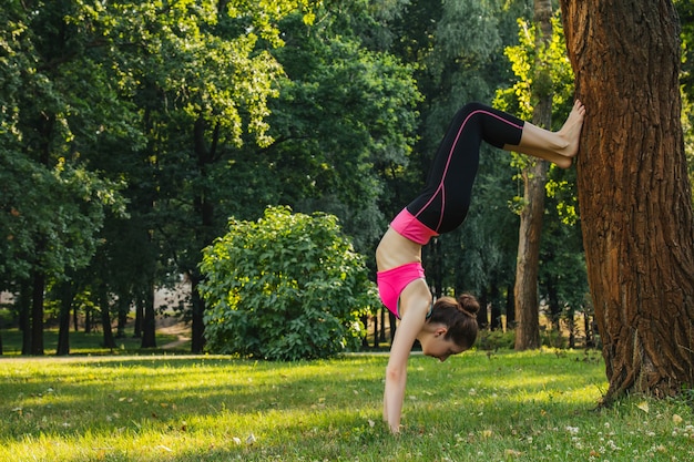 girl in a light tracksuit doing yoga in the park in the afternoon in the summer