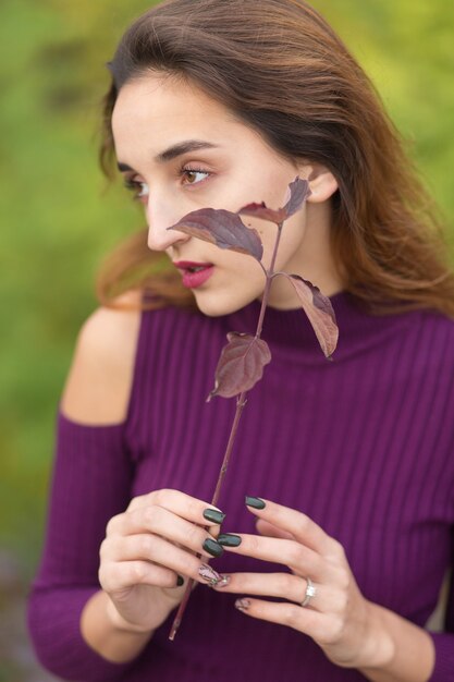 Ragazza in abito lilla sulla natura in autunno, ritratto di una bella ragazza in autunno nella foresta