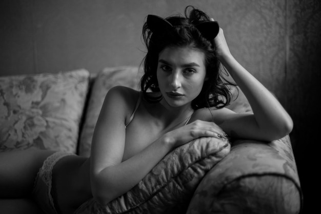 Girl in lingerie and with curly black hair posing in vintage interior black and white photo