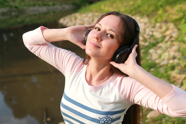 소녀는 야외 헤드폰에서 음악을 듣습니다.