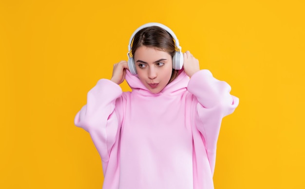 Girl listen music in headphones on yellow background