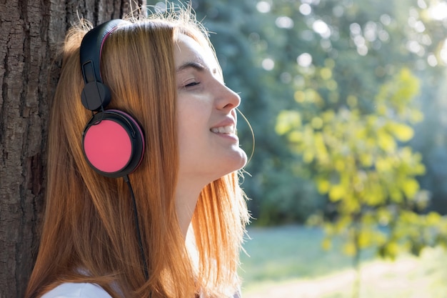 girl listening to music in big pink earphones 