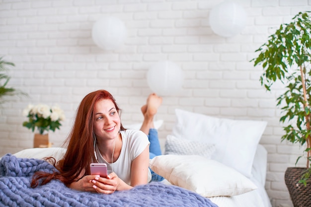 Girl listening to music in headphones in bed.