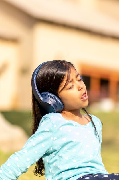 女の子が屋外に座ってヘッドフォンで音楽を聴いている